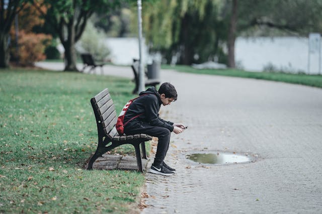 ragazzo solo al telefono su una panchina